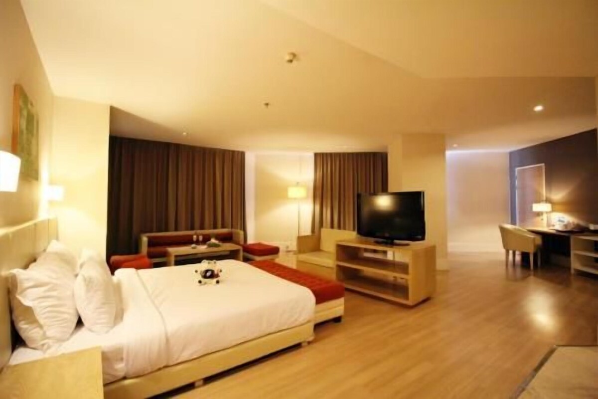 Une chambre d’hôtel avec un lit, une télévision, un bureau et une chaise.