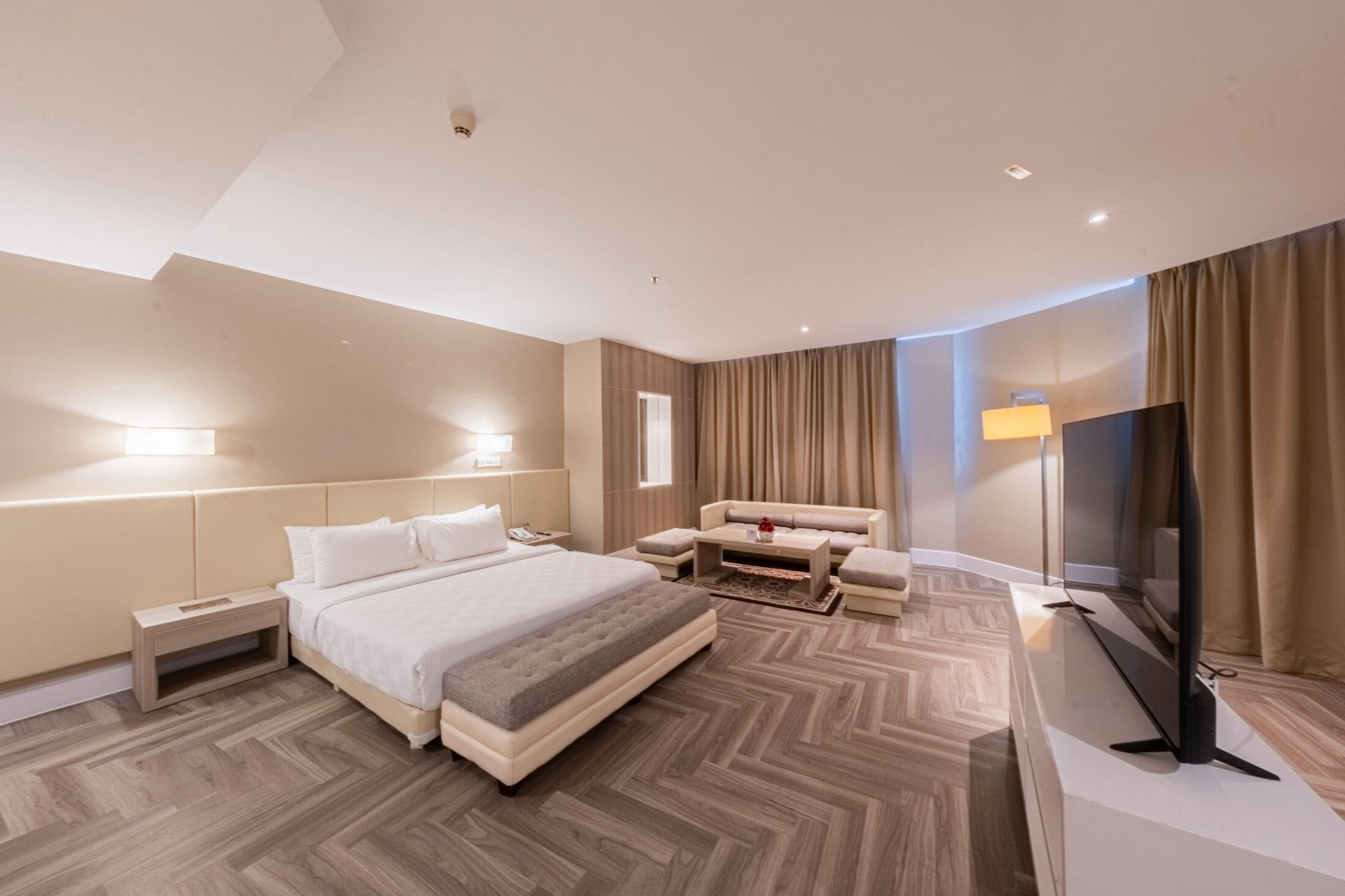 Ein modernes Hotelzimmer mit einem großen Bett, einer Couch, einem Fernseher und einem Schreibtisch.