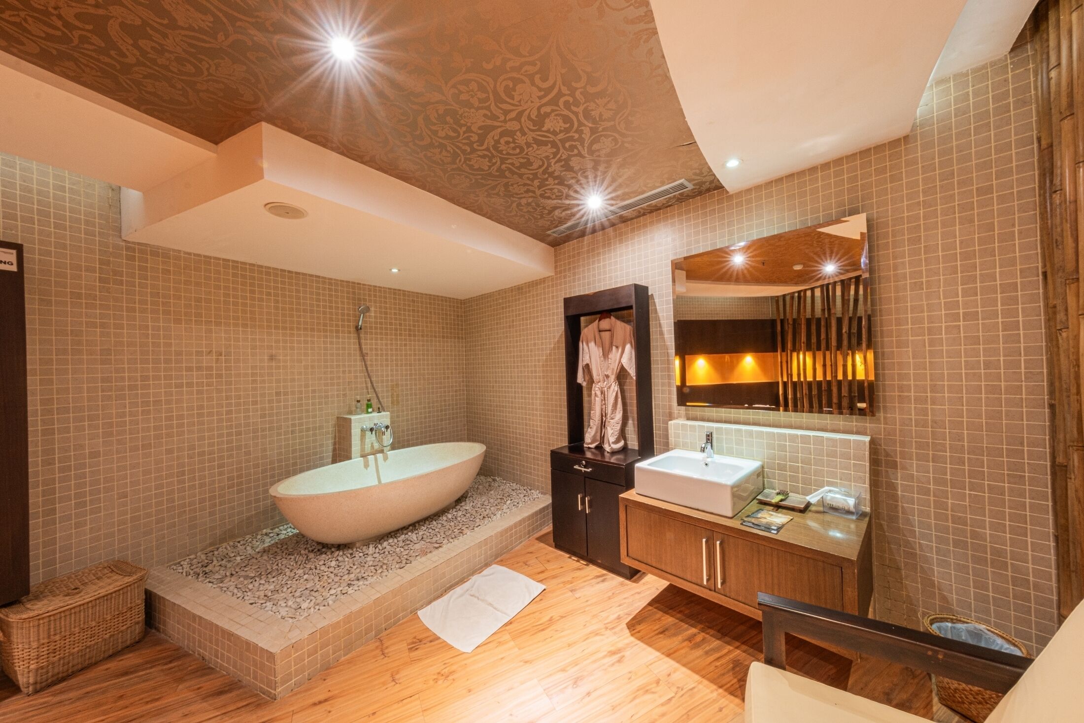 A modern bathroom with a freestanding bathtub, a vanity with a mirror, and a wooden floor.