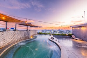 Ein Dachpool mit gewölbtem Design, umgeben von einer Steinmauer und einer Holzpergola.