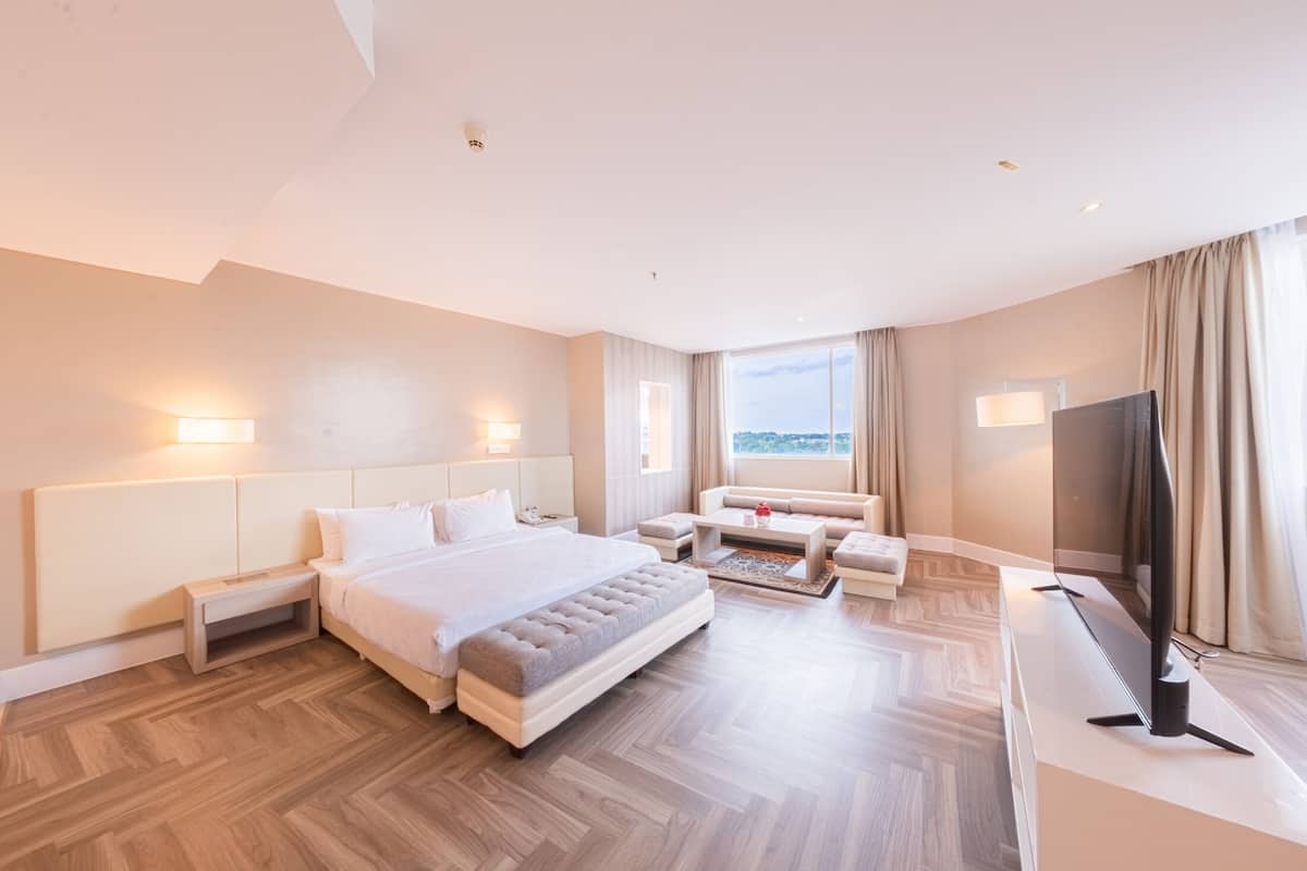 Una habitació d'hotel àmplia amb un llit gran, una televisió de pantalla plana, un sofà i vistes a la ciutat.