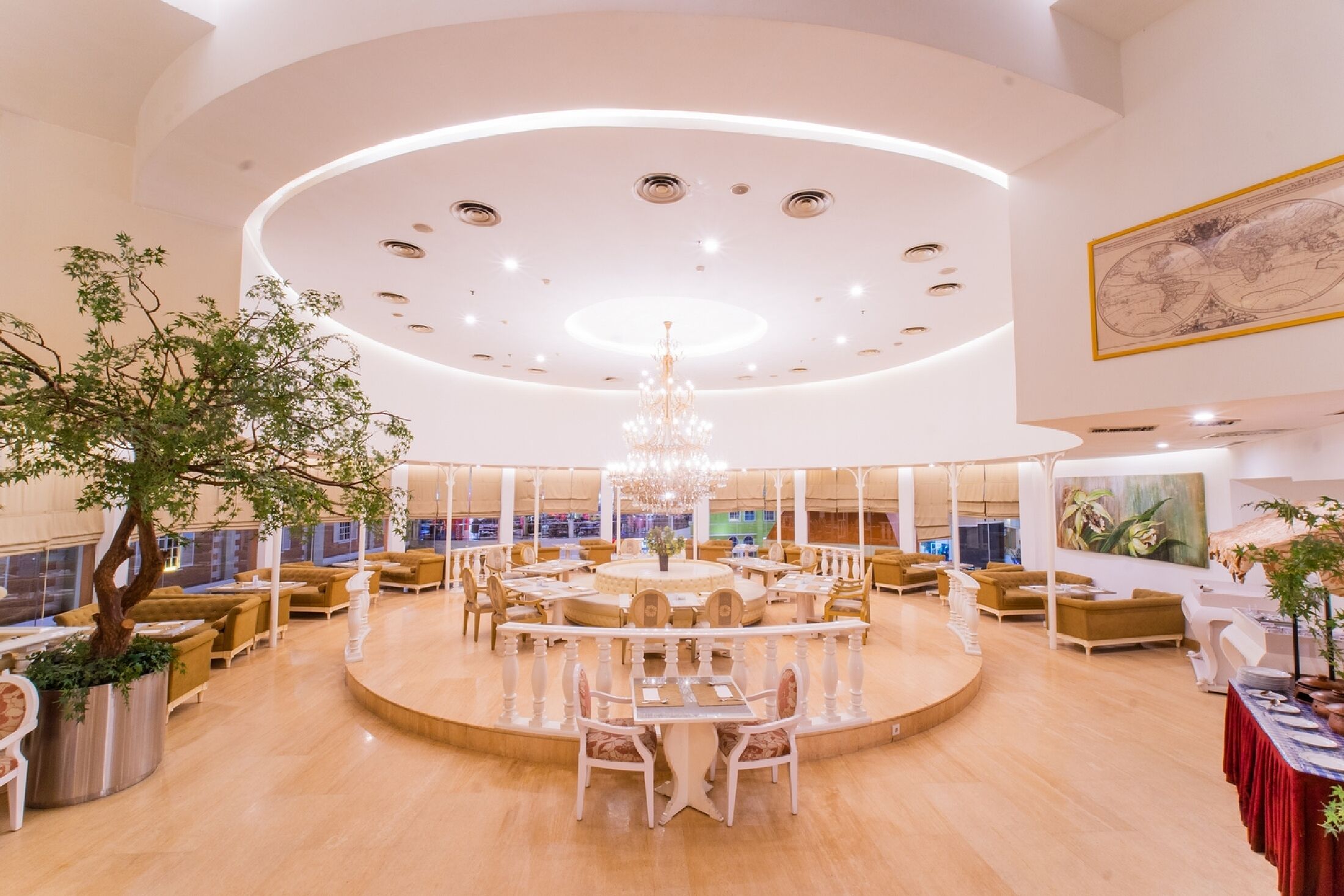 Un vestíbulo amplio con una mesa redonda central, rodeado de asientos y un gran candelabro.