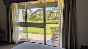 A bedroom with a large window, a bed, and a wicker chair outside. - BreakFree Wirrina Cove (Wirrina Cove)