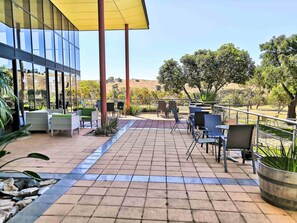 An outdoor patio area with tiled flooring, seating arrangements, and a view of the surrounding landscape. - BreakFree Wirrina Cove (Wirrina Cove)