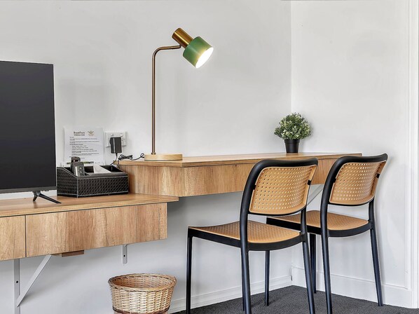 A workspace with a desk, two chairs, a lamp, a computer monitor, a basket, and a small potted plant. - BreakFree Wirrina Cove (Wirrina Cove)