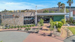 A modern building with a stone facade, a glass entrance, and a landscaped area with pathways and potted plants. - BreakFree Wirrina Cove (Wirrina Cove)
