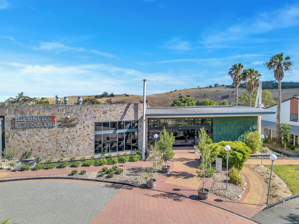 A modern building with a stone facade, a glass entrance, and a landscaped area with pathways and potted plants. - BreakFree Wirrina Cove (Wirrina Cove)