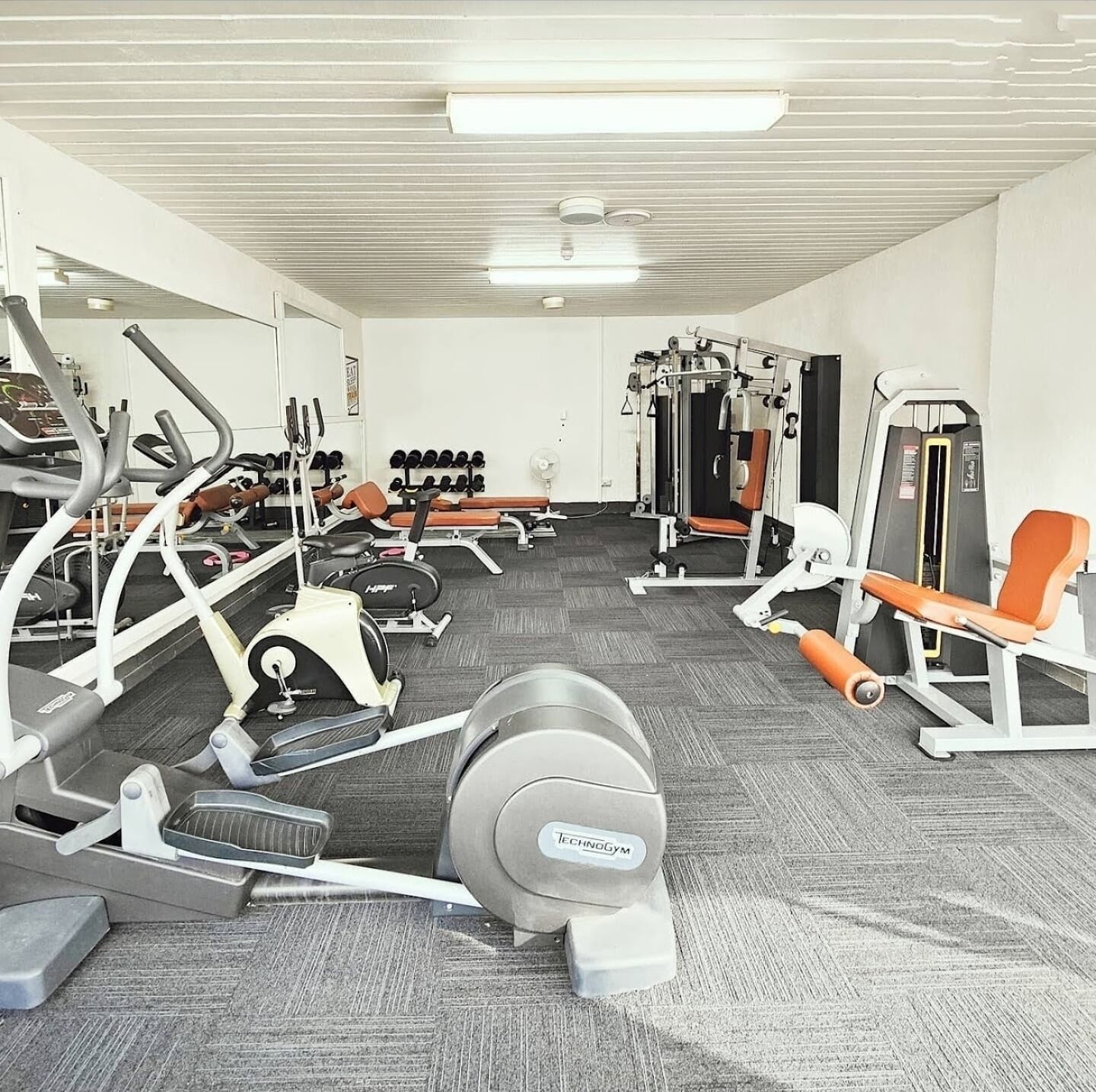 A gym with various exercise equipment including treadmills, weight machines, and free weights.