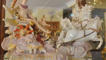 A decorative ceramic sculpture with a figure on a chariot pulled by horses, surrounded by floral patterns.