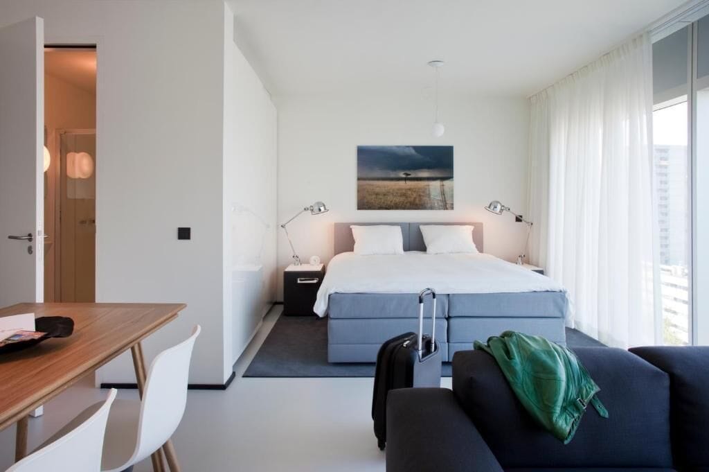 Une chambre d’hôtel moderne équipée d’un lit, de tables de chevet, d’un bureau et offrant une vue sur l’extérieur.