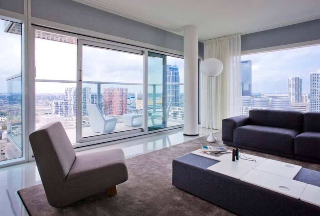 Un salon moderne avec une grande fenêtre, un canapé, une table basse et un fauteuil.