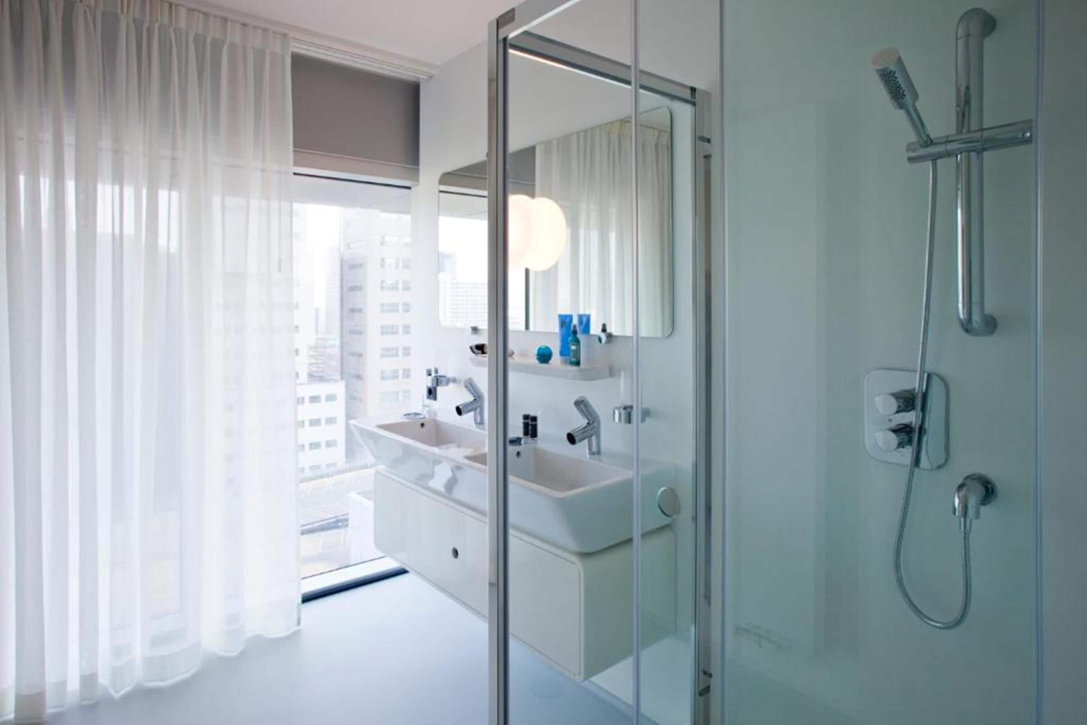 Un baño moderno con cabina de ducha de vidrio, tocador doble y un espejo grande.