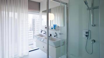 Un baño moderno con cabina de ducha de vidrio, tocador doble y un espejo grande.