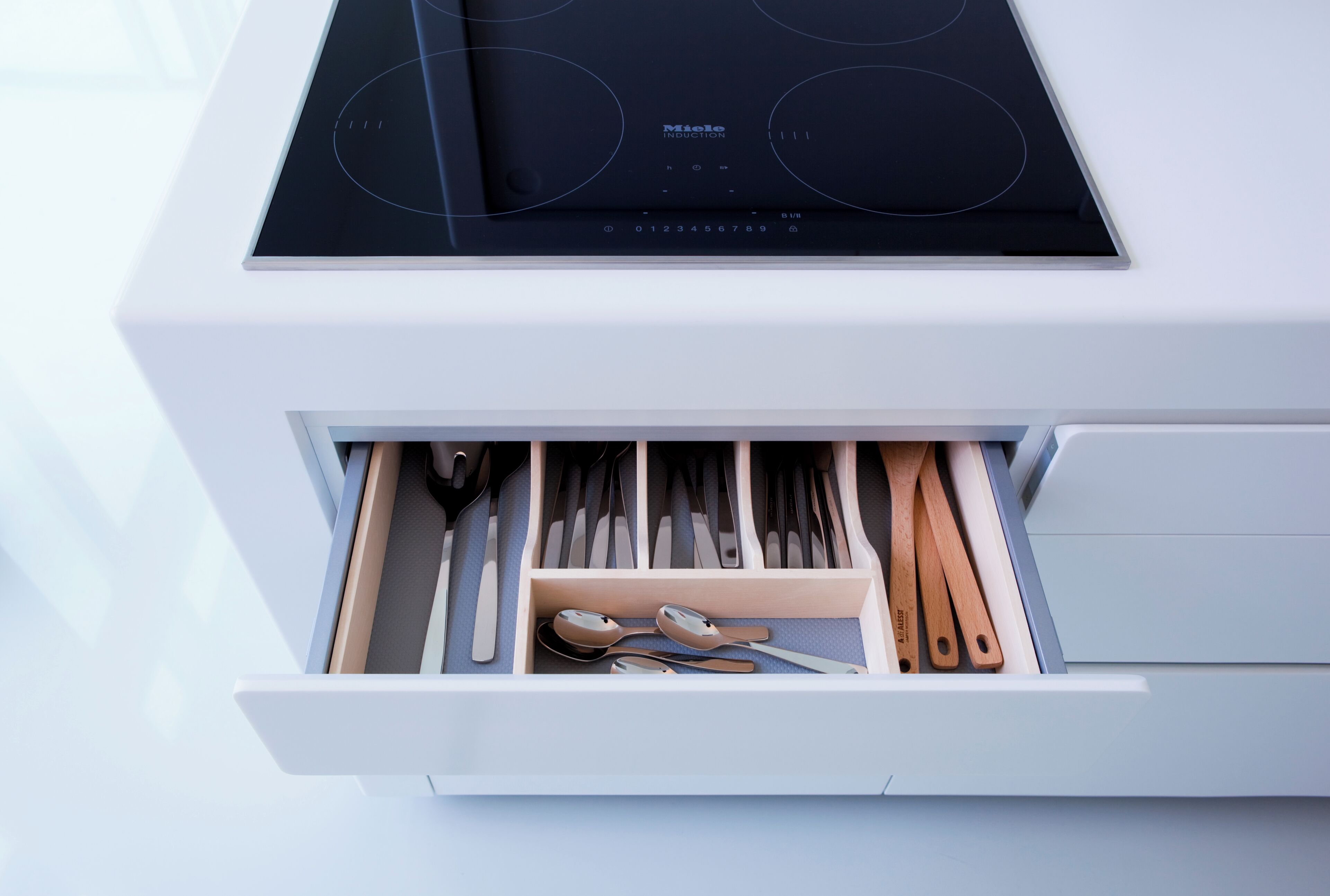 A kitchen drawer with utensils and a stove.