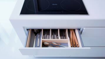 A kitchen drawer with utensils and a stove.