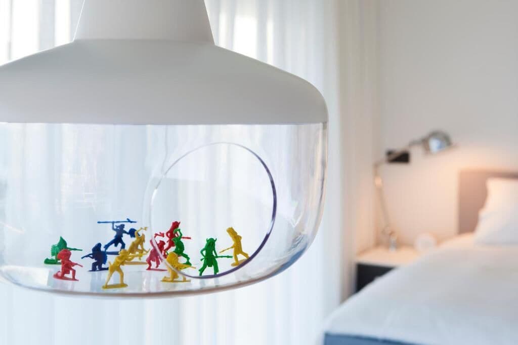 A clear glass globe with colorful figurines inside, placed on a white stand.
