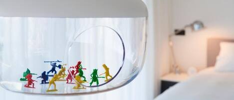 A clear glass globe with colorful figurines inside, placed on a white stand.