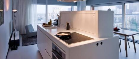 A modern kitchen with a built-in stove, a dining area with a table, and a view of the city through large windows.