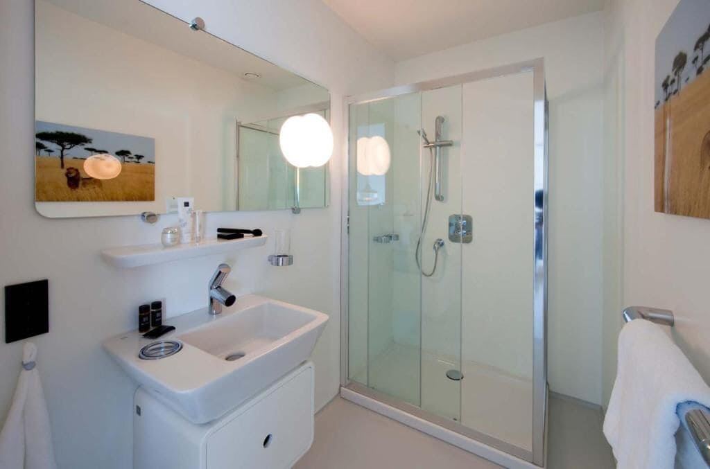 Une salle de bain moderne avec une douche à parois de verre, un lavabo blanc et un grand miroir.