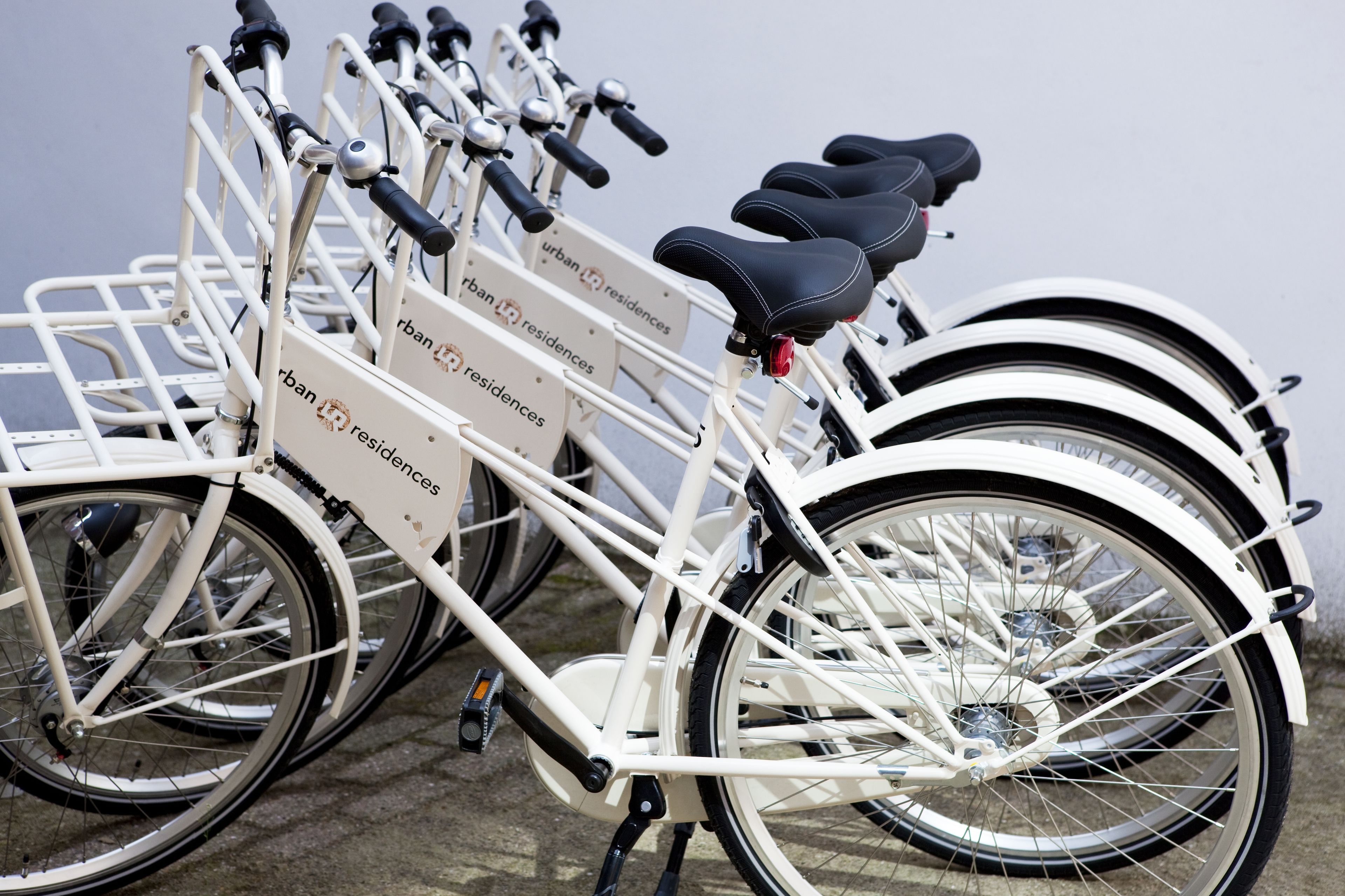 Un vélo blanc doté de plusieurs sièges et d’un porte-bagages, portant l’inscription « résidences urbaines LR ».