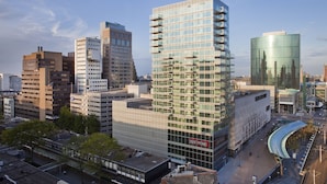 Un moderno edificio de gran altura con fachada de vidrio, rodeado de otras construcciones urbanas.