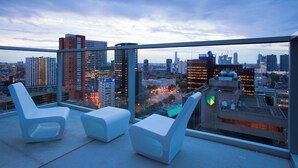 Terraza en la azotea con sillones blancos y vistas panorámicas de la ciudad.
