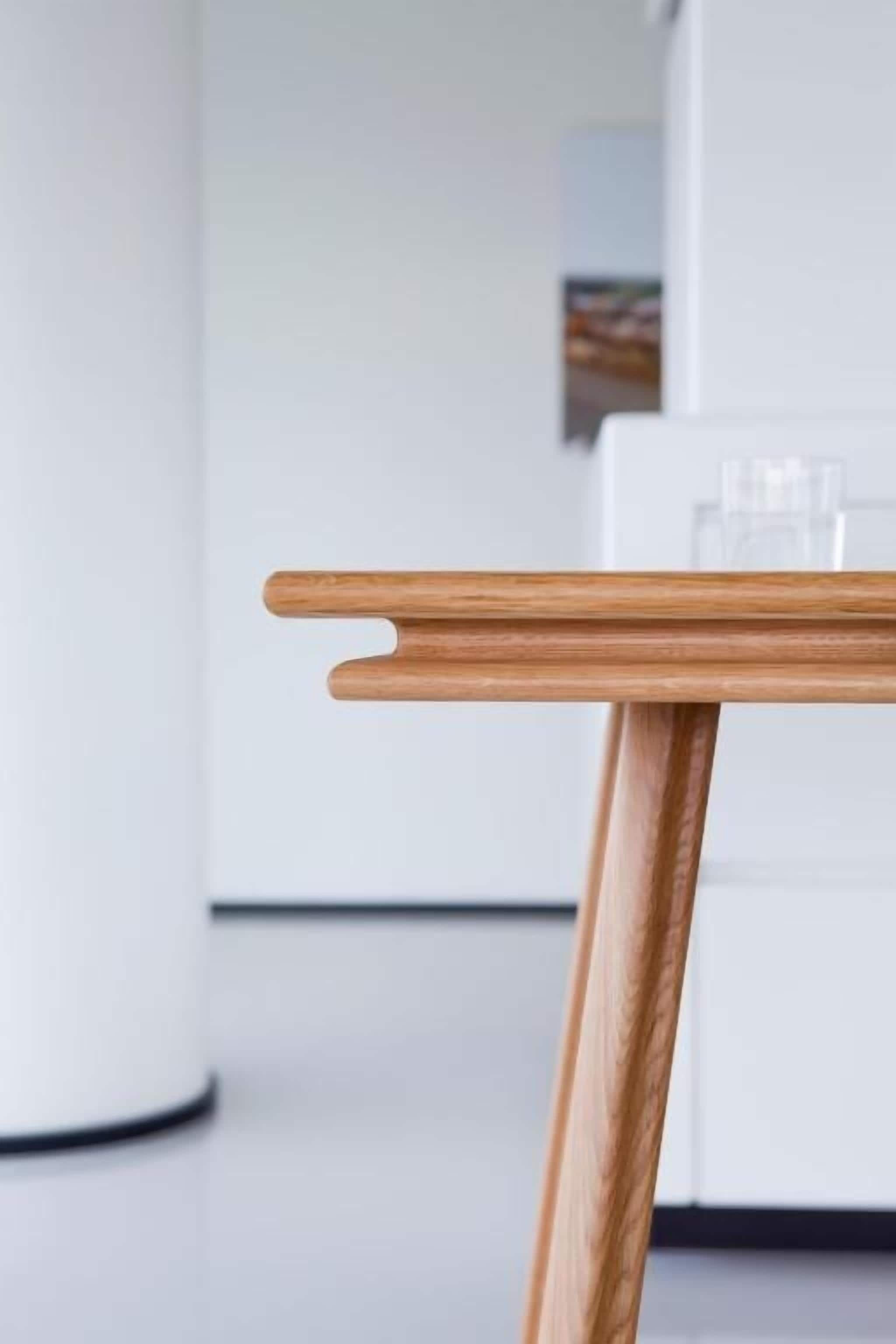 Een moderne keuken met een houten tafel en witte kastjes.