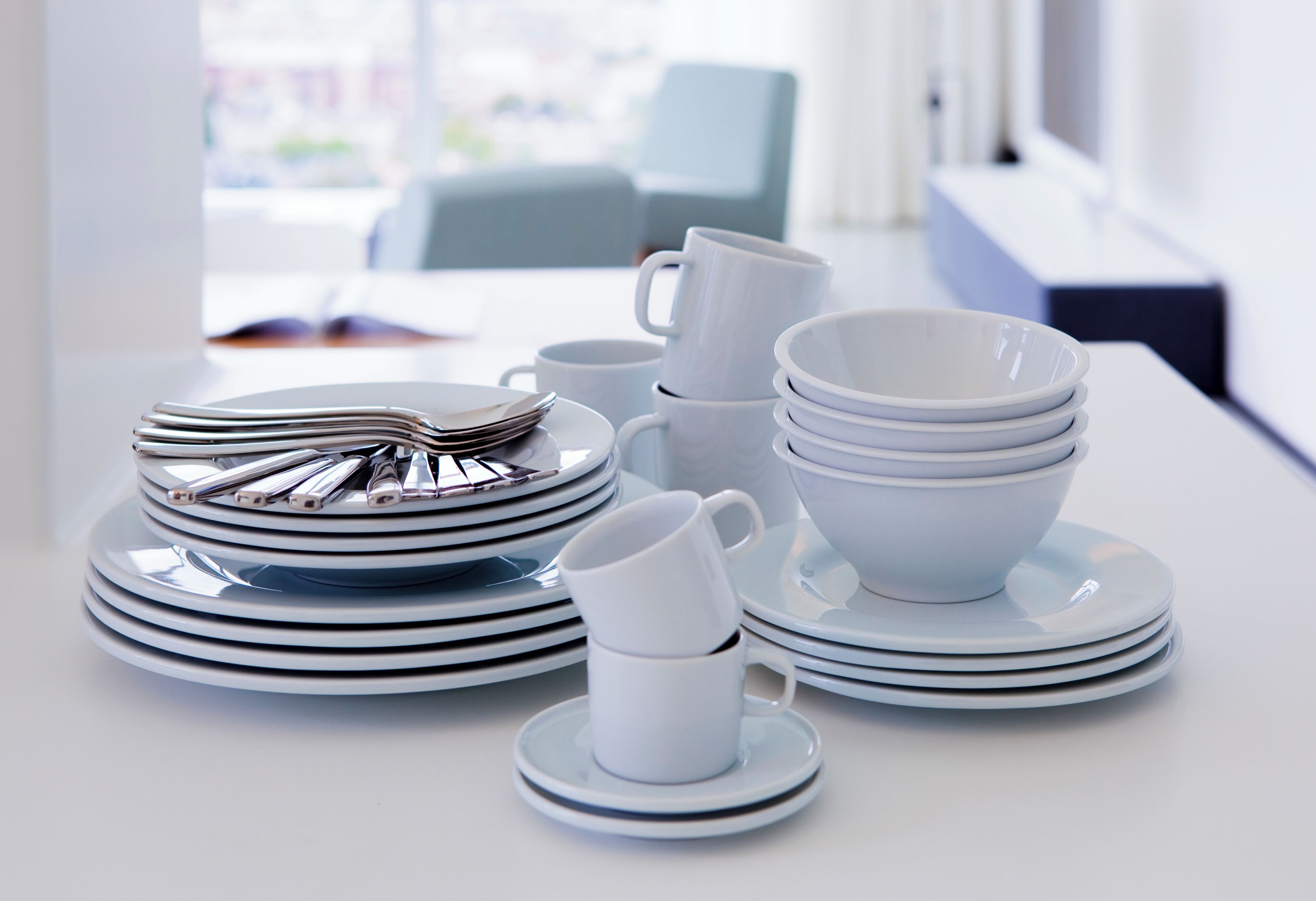 Una mesa ordenada con platos, tazones y una taza apilados, lo que sugiere un comedor en un hotel moderno.
