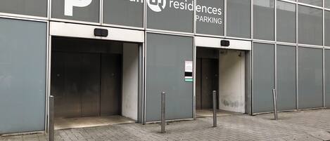 A modern building with a large glass facade, featuring a prominent 'Urban Residences' sign and a 'Parking' sign.