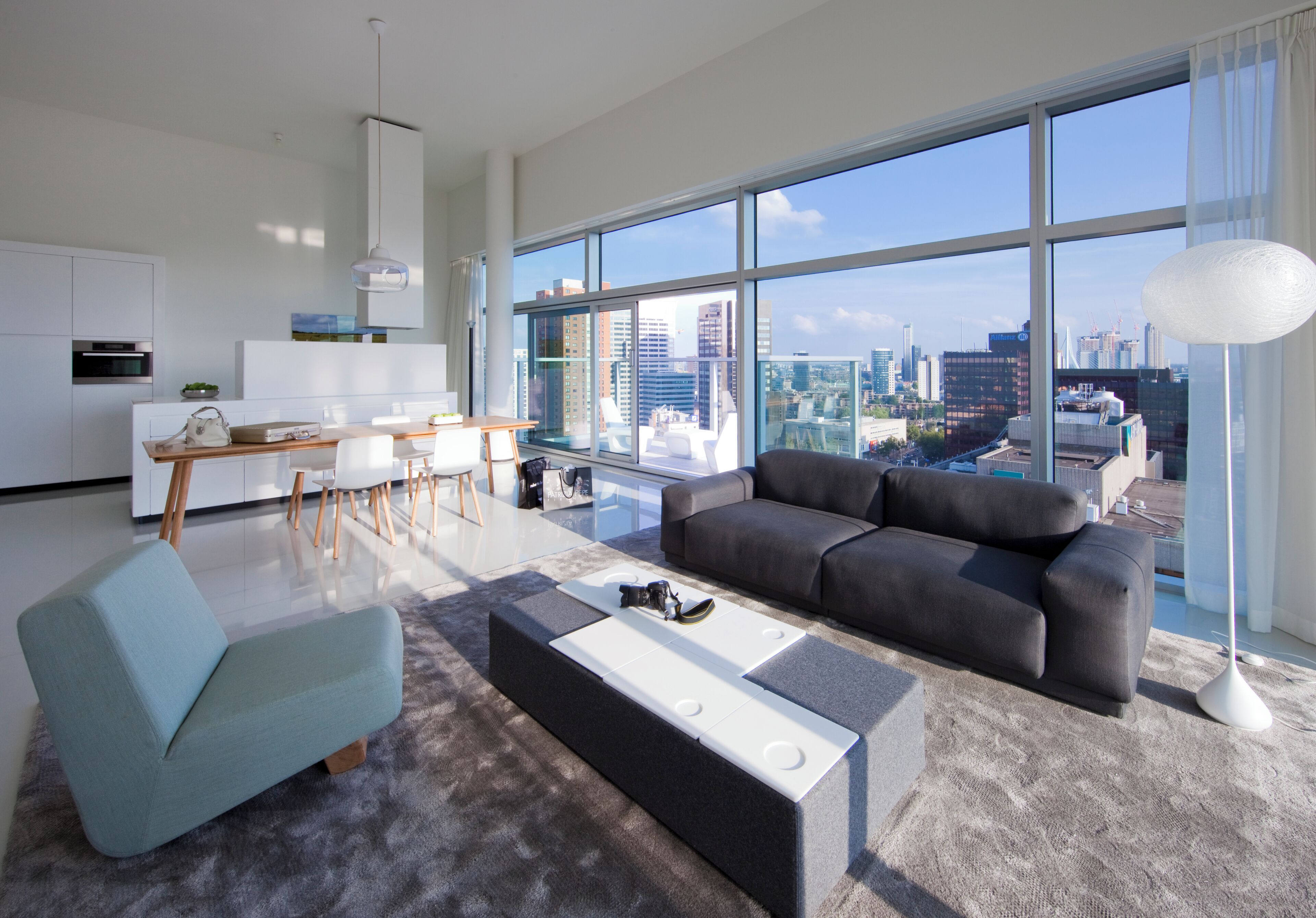 A modern living room with a sofa, a coffee table, and a dining area with a table and chairs.