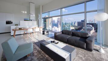 A modern living room with a sofa, a coffee table, and a dining area with a table and chairs.