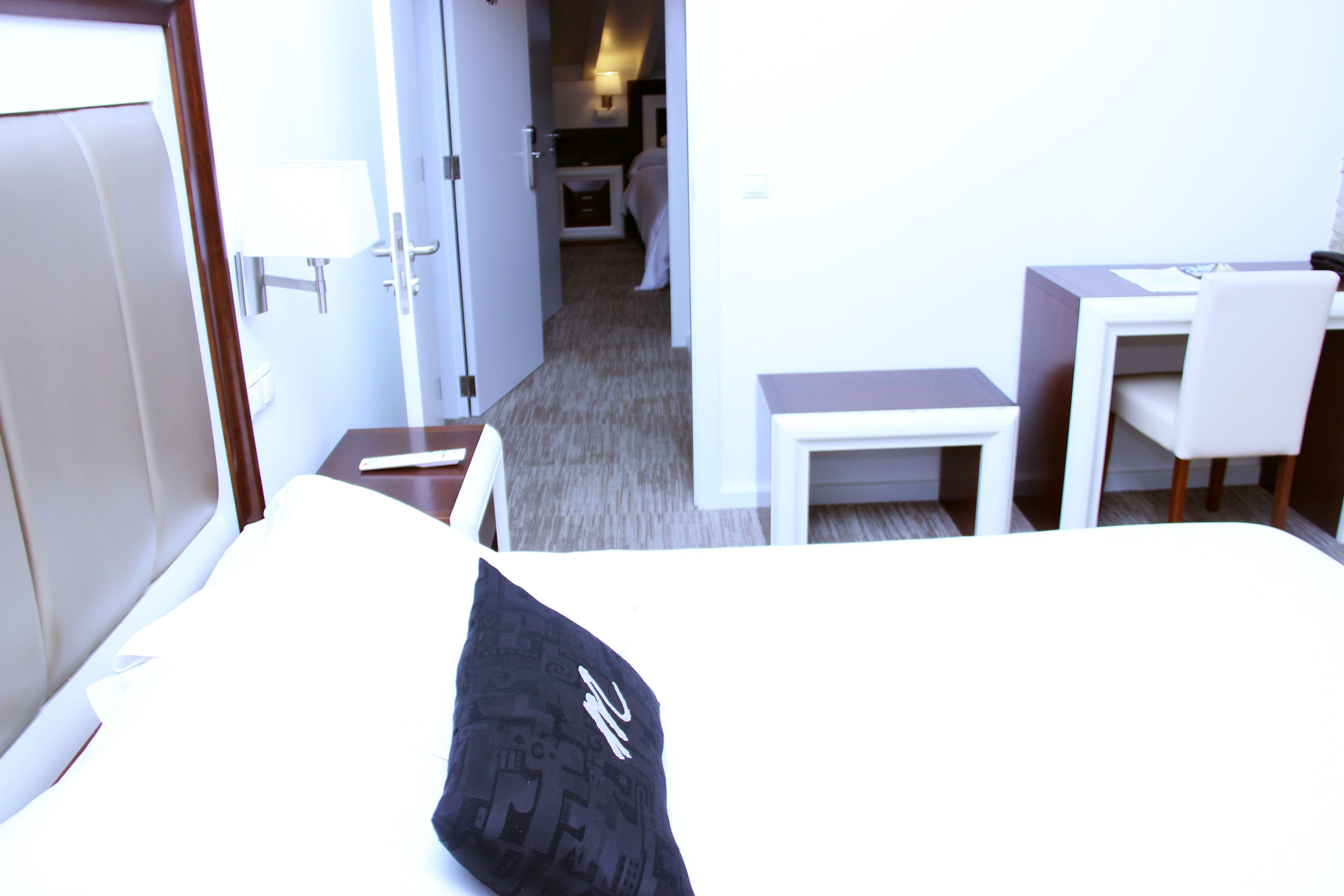 A hotel room with a bed, a desk, a chair, and a small table.
