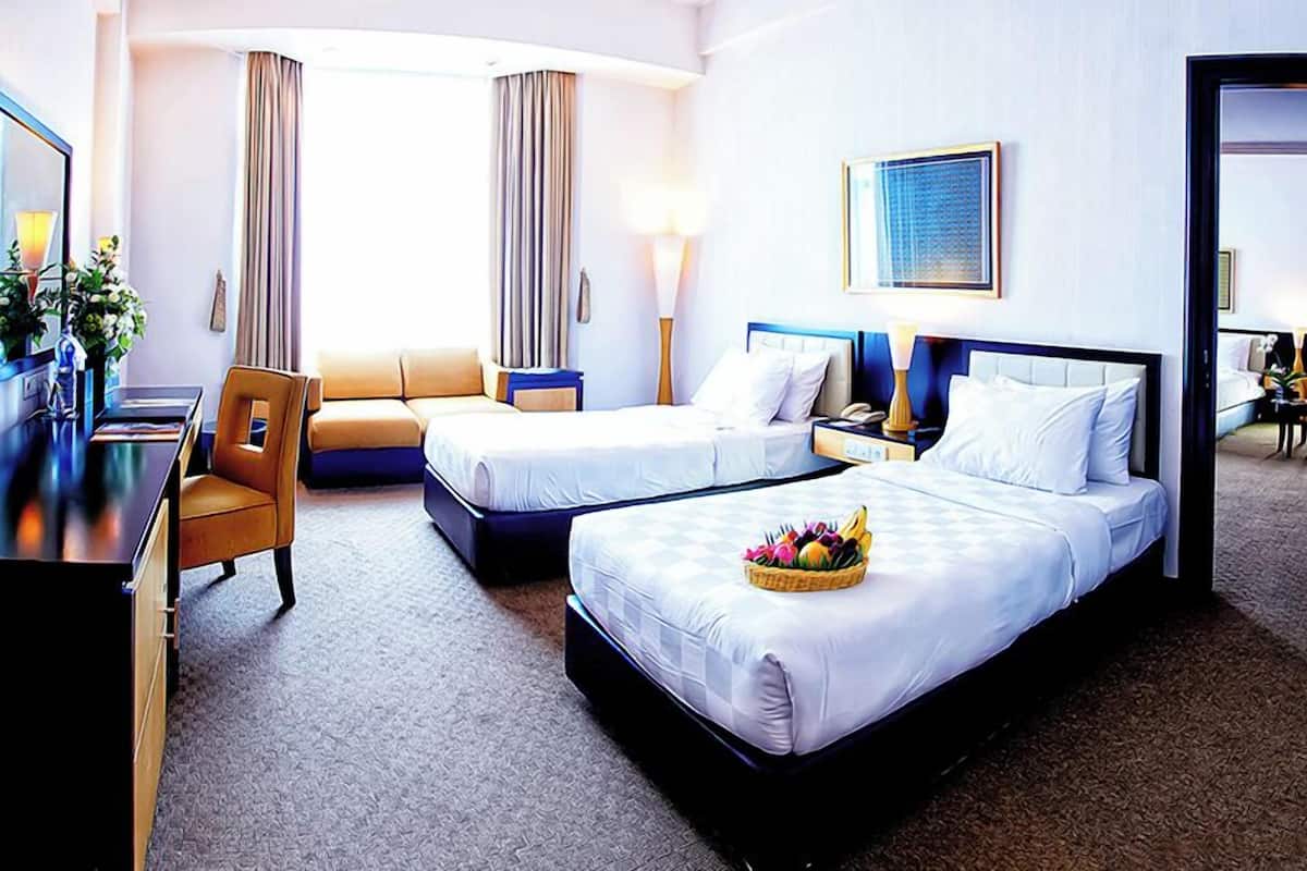 A hotel room with two beds, a desk, and a chair.