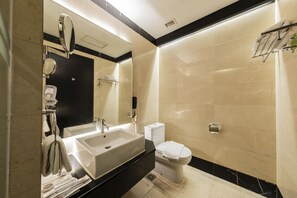 Un baño moderno con un lavamanos grande, espejo, inodoro y toallero.