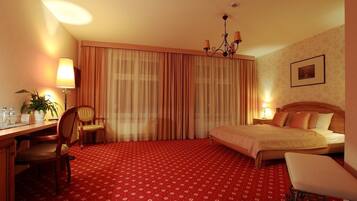 Una habitación de hotel con cama, escritorio, silla, lámpara y candelabro.