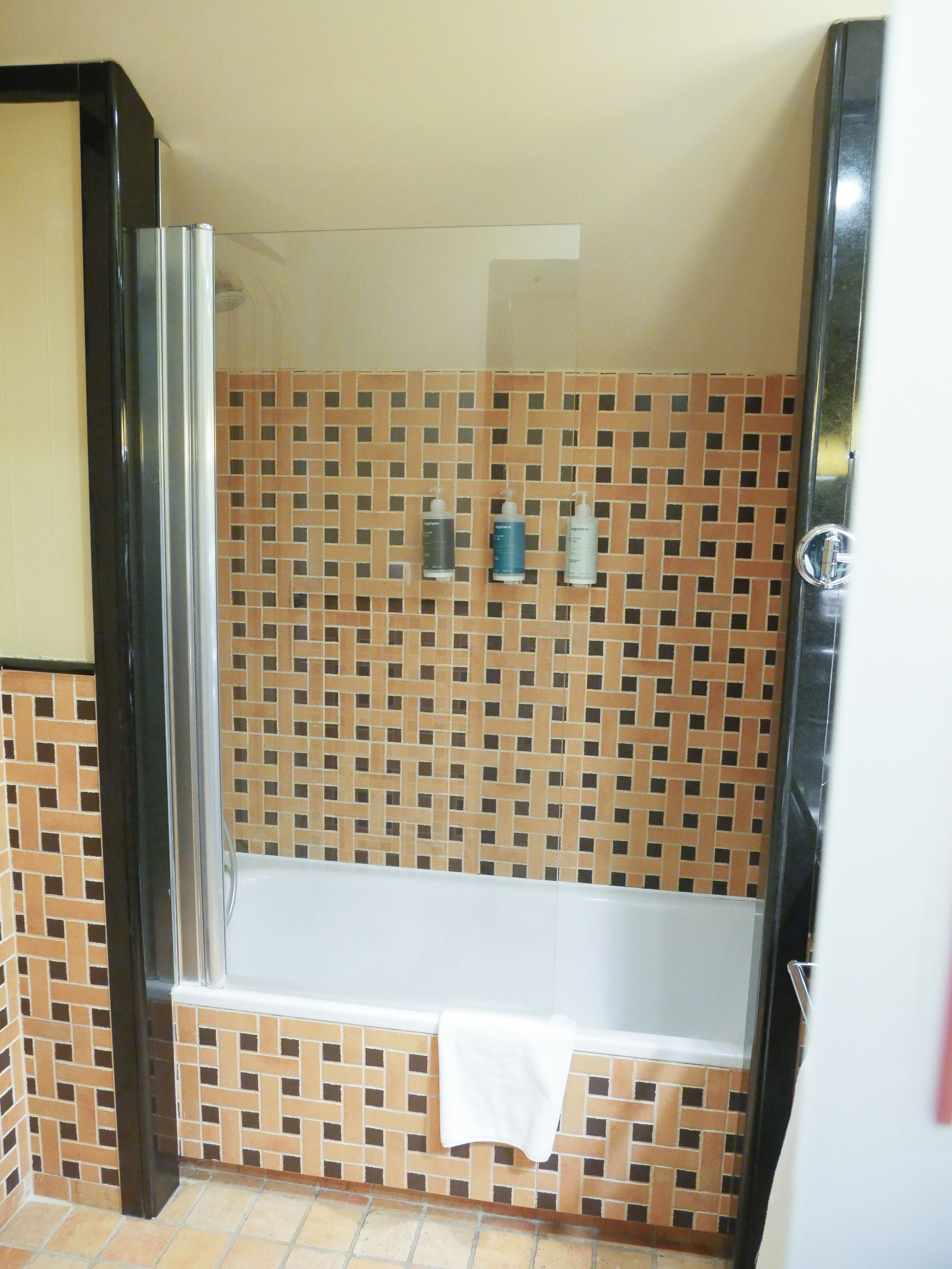 A bathroom with a tiled shower wall, a bathtub, and a glass shower enclosure.