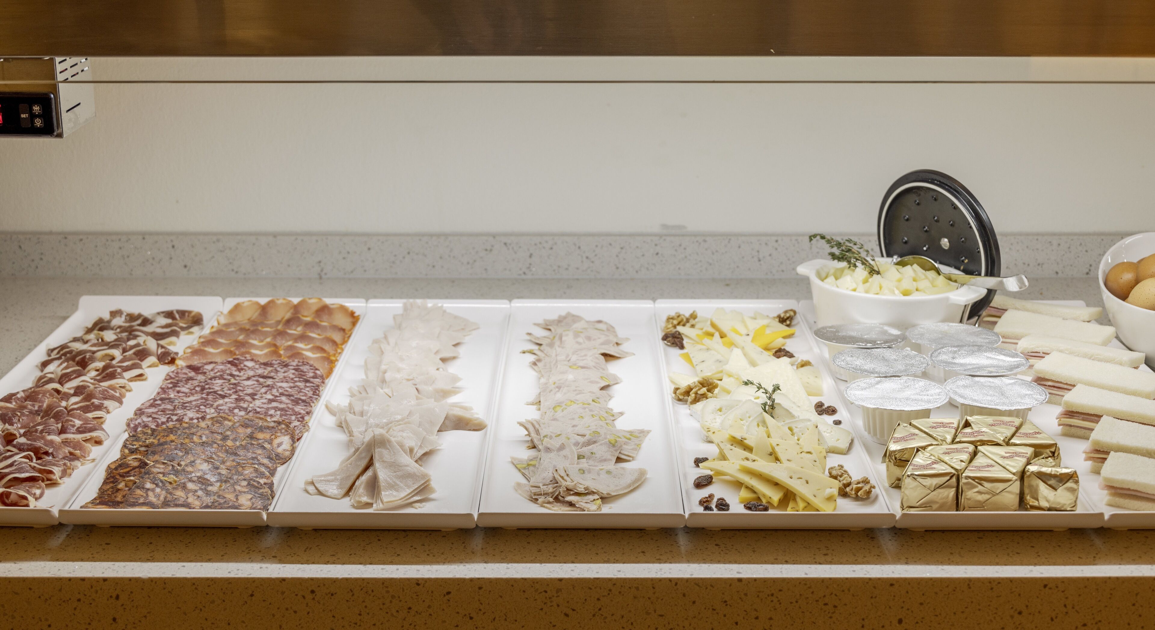 A buffet table with various food items including meats, cheeses, and pastries.