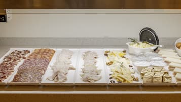 A buffet table with various food items including meats, cheeses, and pastries.