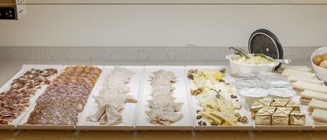 A buffet table with various food items including meats, cheeses, and pastries.