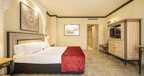 A hotel room with a large bed, a TV, a wooden cabinet, and a framed picture on the wall.