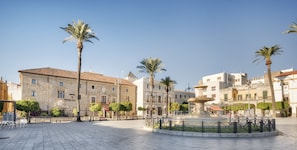A historic building with a courtyard, palm trees, and a fountain.