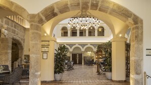 A spacious lobby with stone arches, a chandelier, and seating areas.