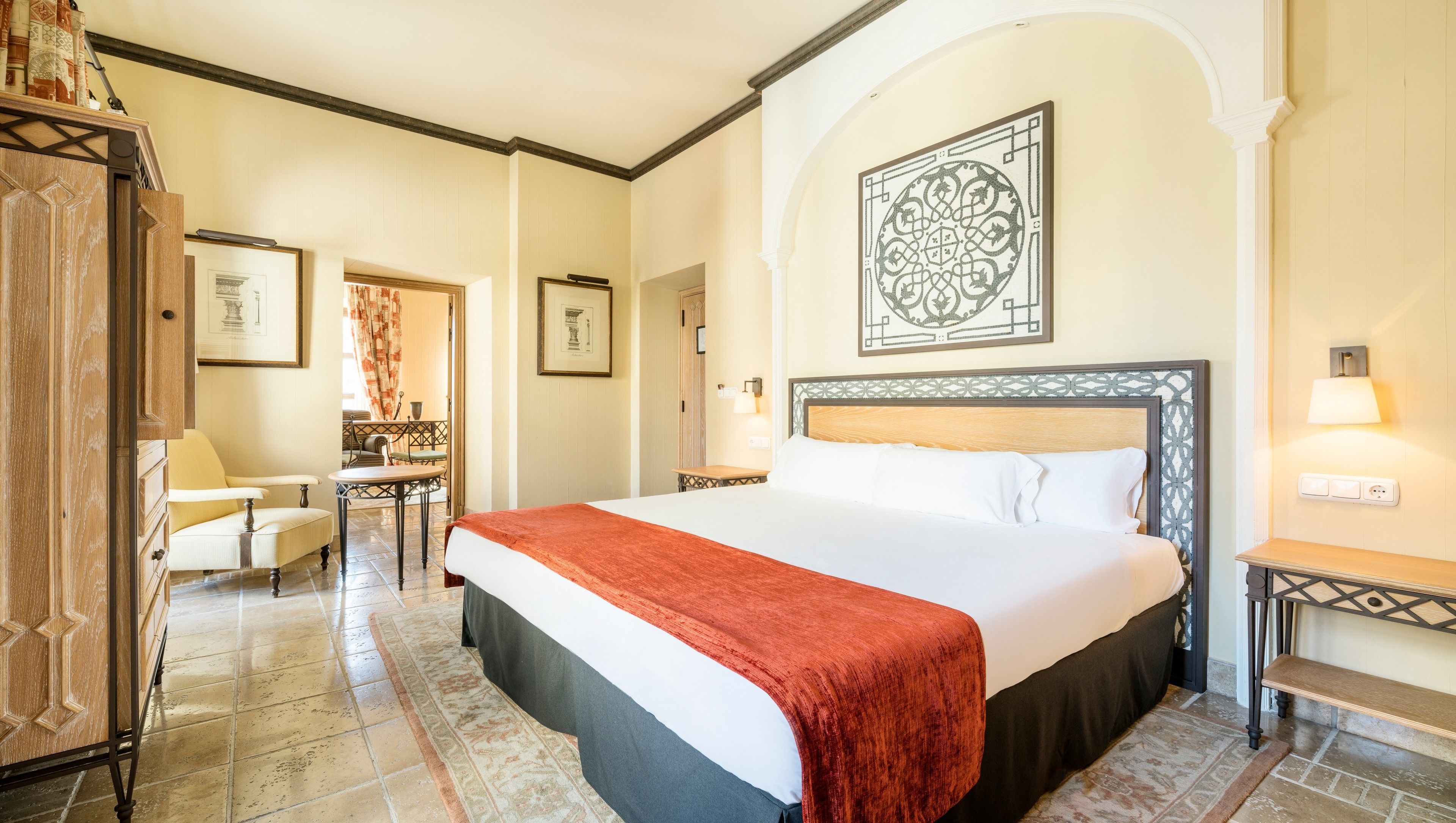A hotel room with a large bed, a desk, a chair, and a small table.