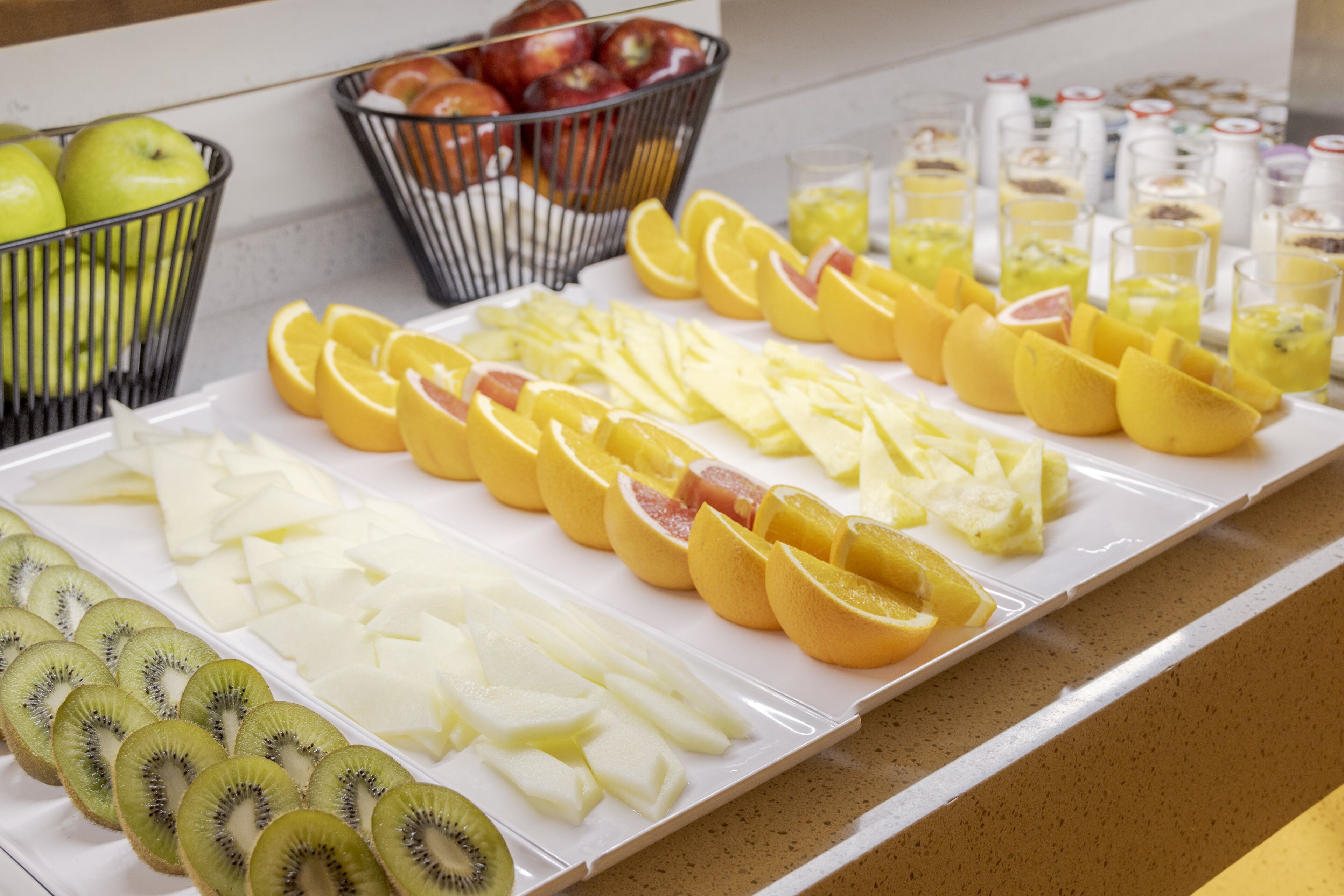 A buffet table with sliced fruits and beverages.