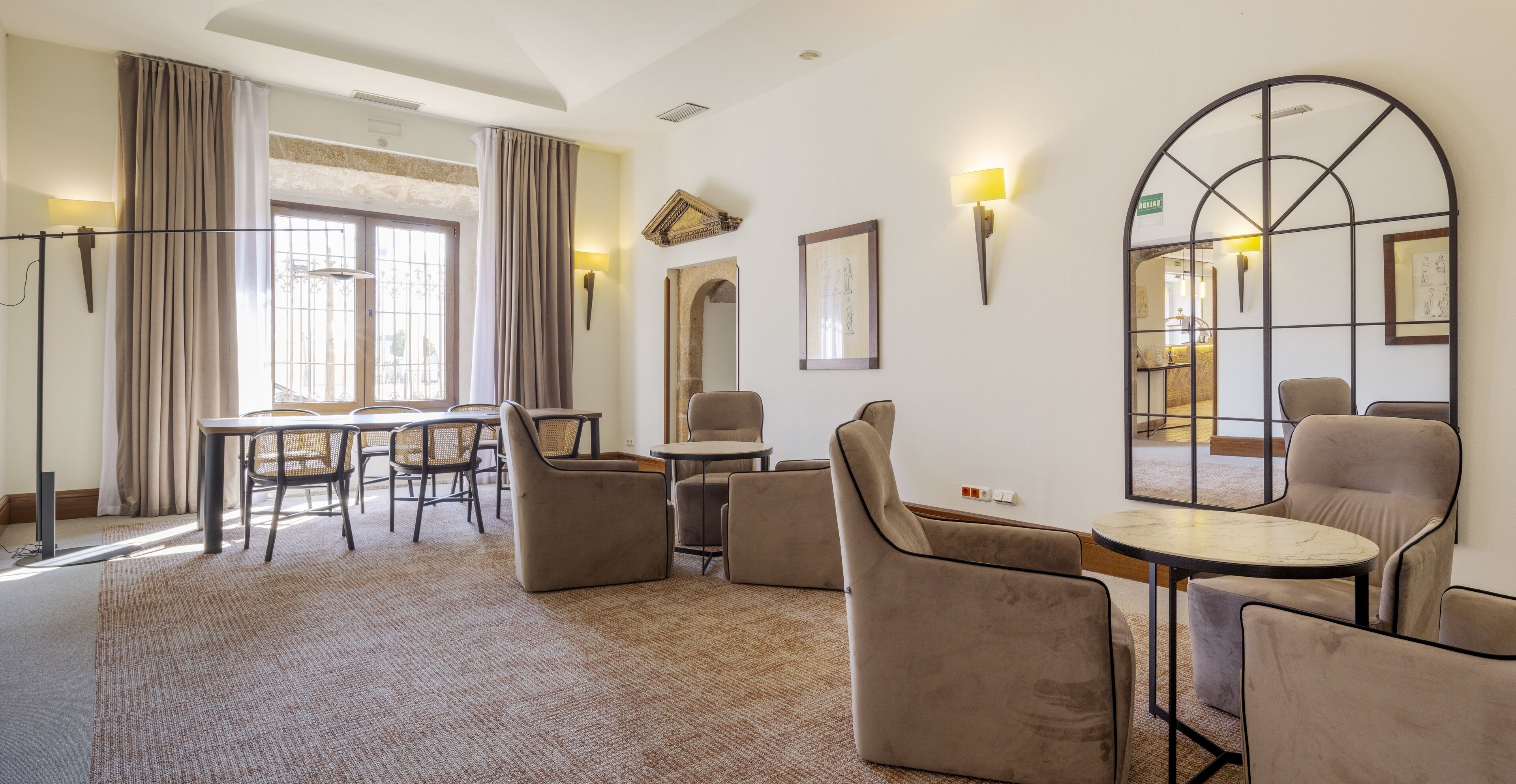 Habitación de hotel con zona de comedor, un espejo grande y vistas al exterior.