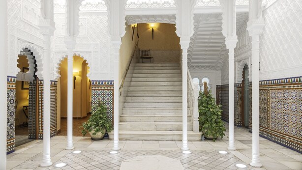 A grand staircase with ornate white arches and columns, leading to a higher level.