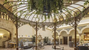 A covered outdoor seating area with wrought iron furniture and a tiled floor.