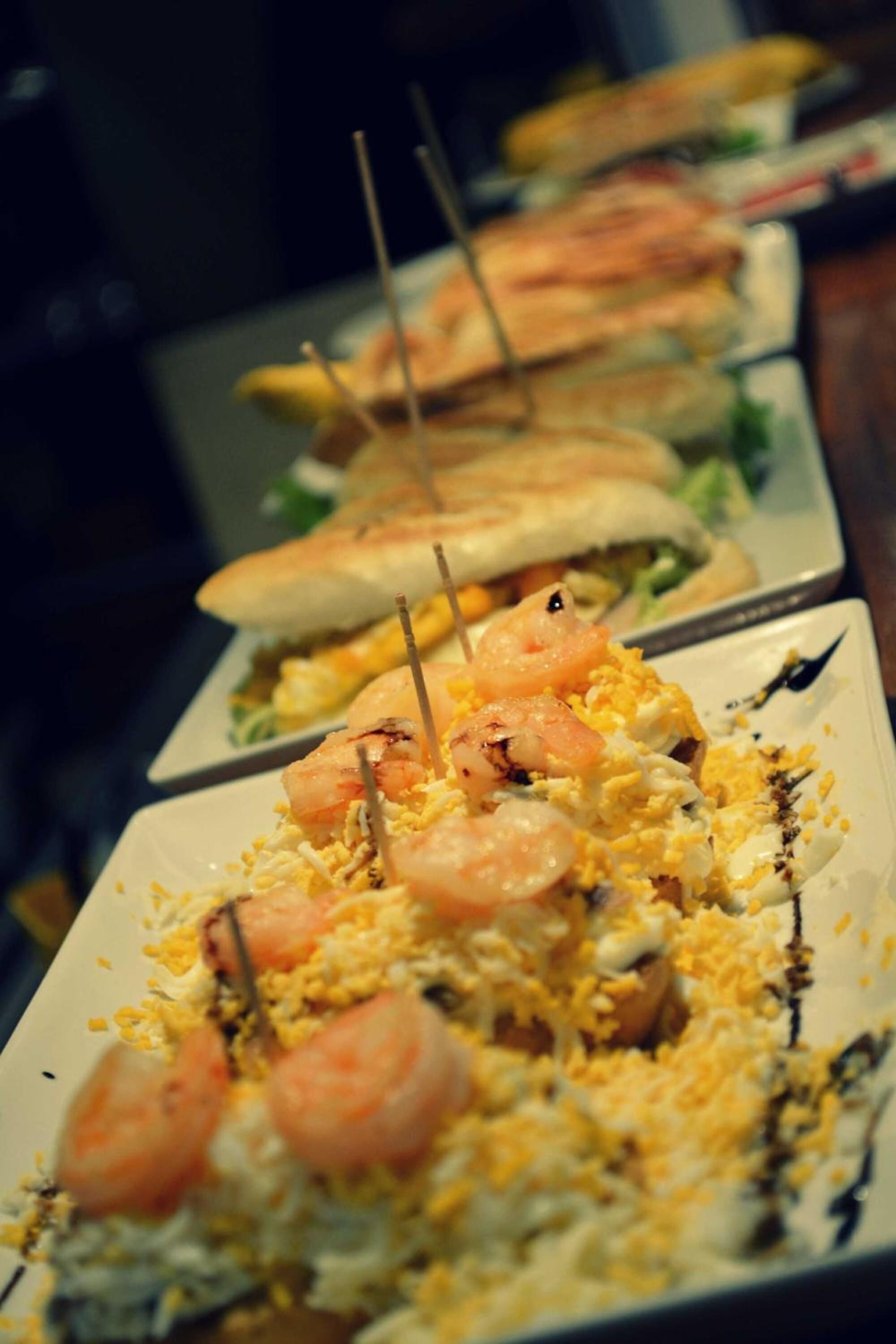 A buffet table with various dishes, including shrimp and egg-based items, arranged on rectangular plates.