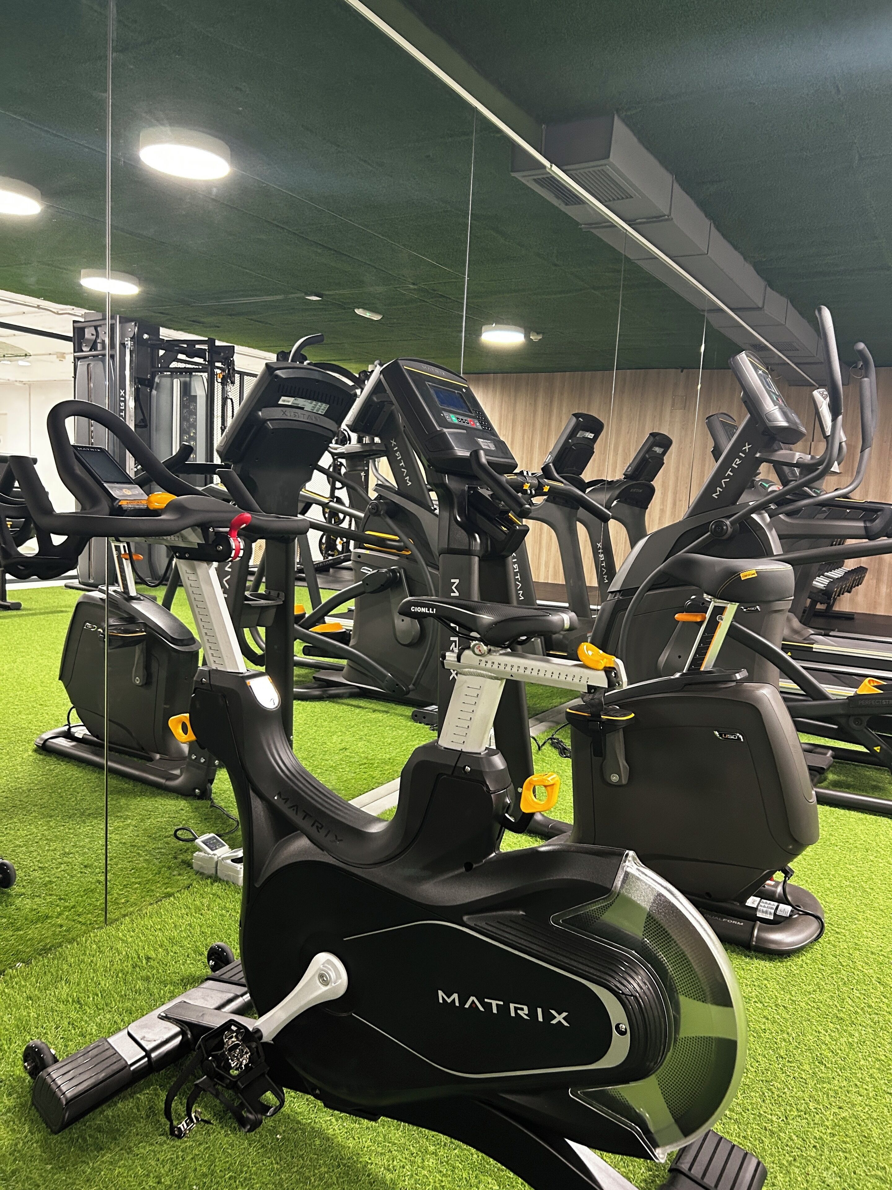 Un gimnasio con varias bicicletas estáticas y cintas de correr, equipado con maquinaria de marca Matrix.