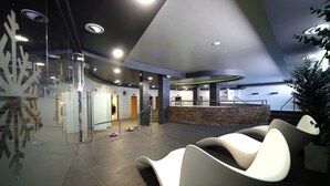 Una hall moderna con sedute curve, una reception e una scalinata.